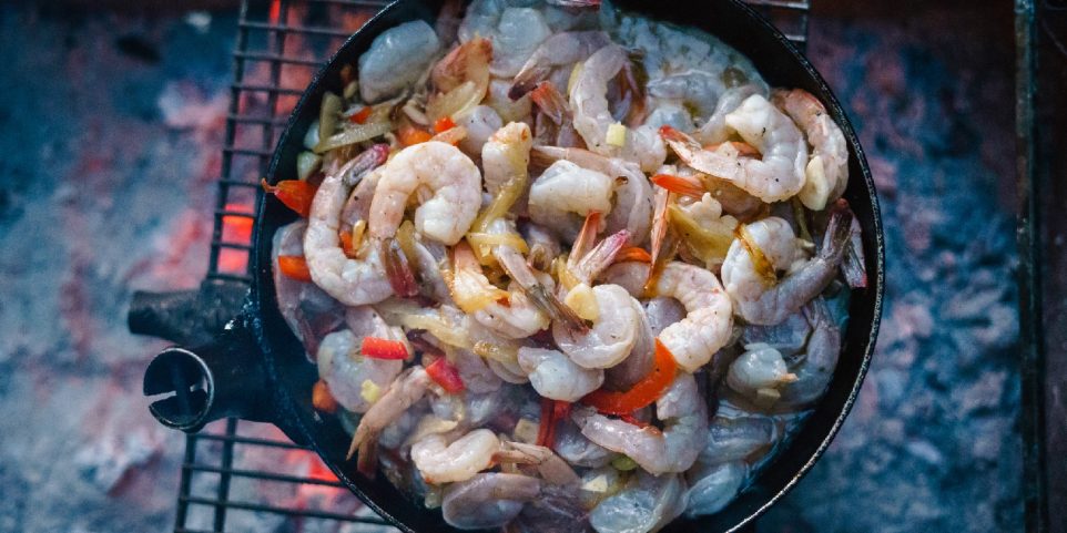 Pan with shrimps on open fire
