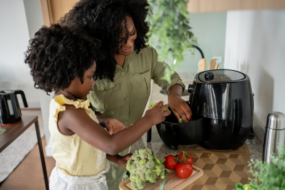 Mother teaching daughter how to prepare vegetables in an oil-free fryer