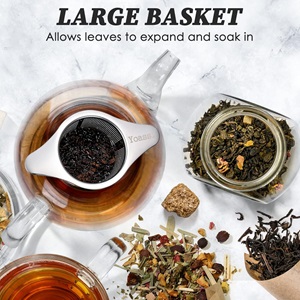 The Yoassi Tea Infuser in a teapot, surrounded by different herbs and loose-leaf teas.